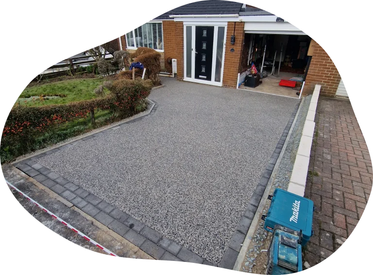 New grey resin-bound driveway with charcoal block edging outside a brick house and garage in Durham