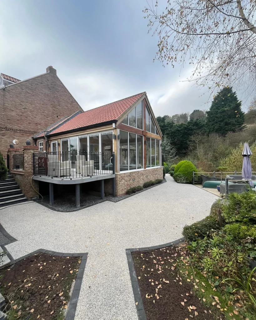 Beige resin-bound driveway with stone block edging leading to a double garage at a Durham home